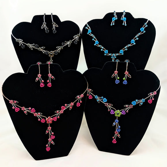 Set of necklaces and earrings on black display stands with a white background