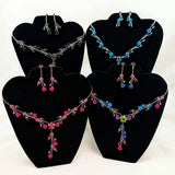 Set of necklaces and earrings on black display stands with a white background
