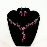 Jewelry set with pink floral necklace and earrings on a black stand.