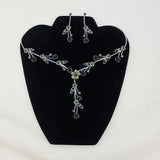 Jewelry set with black floral necklace and earrings on a black stand.