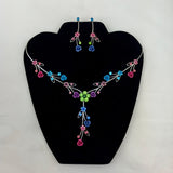 Jewelry set with colorful floral necklace and earrings on a black stand.