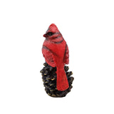 Red cardinal bird figurine on a pine cone against a white background