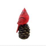 Red cardinal bird figurine on a pine cone against a white background