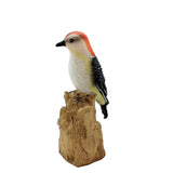 Woodpecker figurine on a wooden stump against a white background