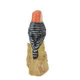 Woodpecker figurine on a wooden stump against a white background