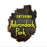 Wooden sign shaped like the Adirondack Park with 'Entering Adirondack Park' text on a white background