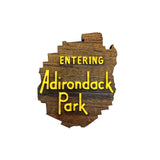 Wooden sign shaped like the Adirondack Park with 'Entering Adirondack Park' text on a white background